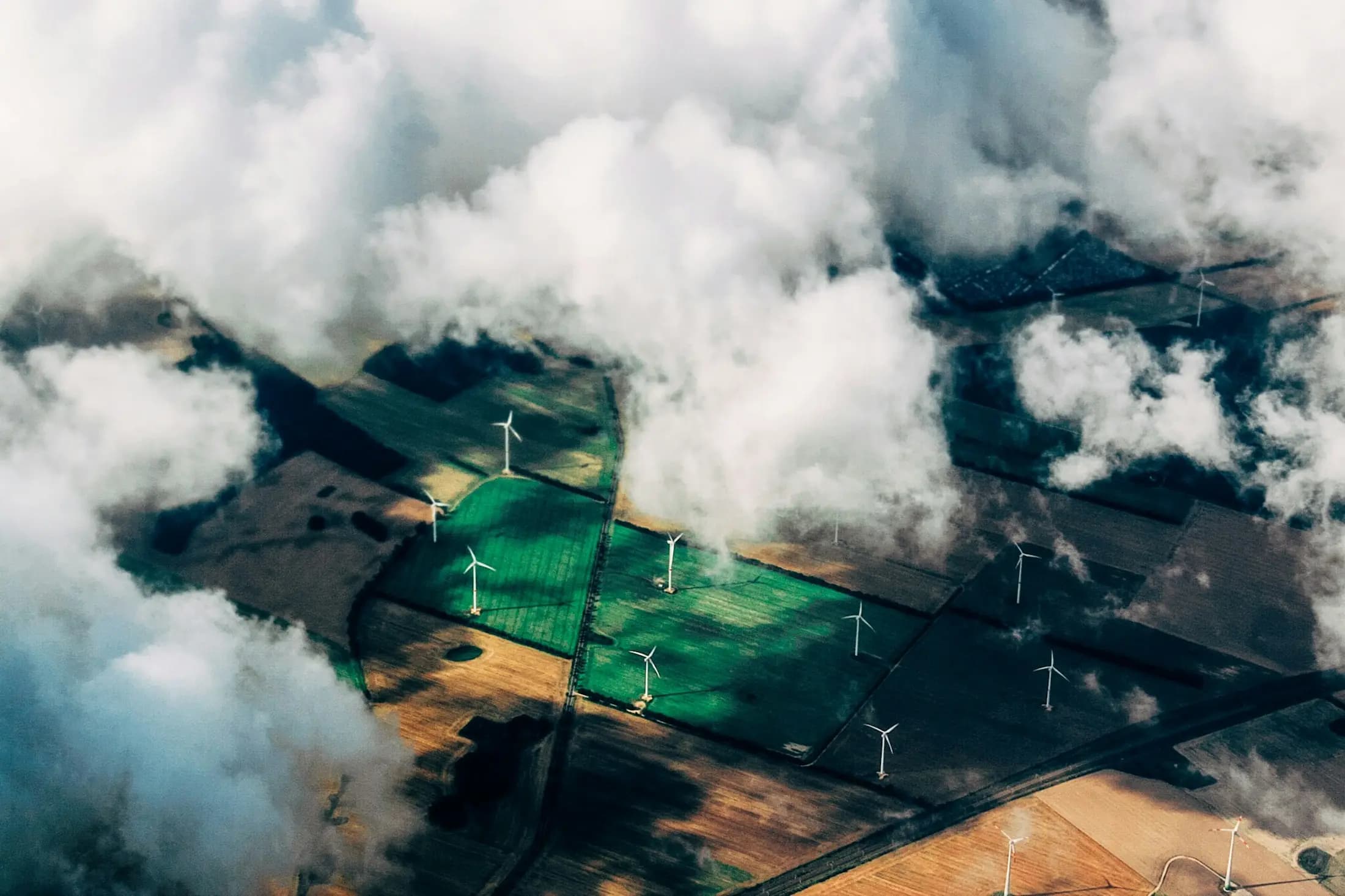 Wind turbines operating across agricultural fields beneath low clouds